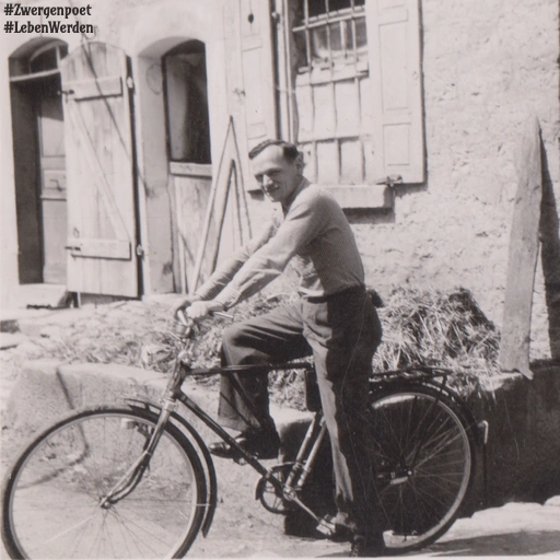 Das alte Foto zeigt einen Mann mit einem Fahrrad vor den Ställen eines Bauernhofes.